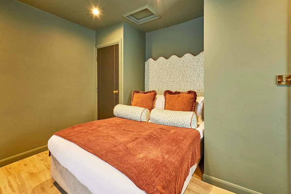 A bedroom with a bed covered in a rust-colored blanket and matching cushions.