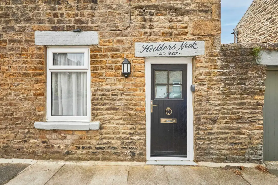 A dark entrance door and curtained window are set in a stone facade.