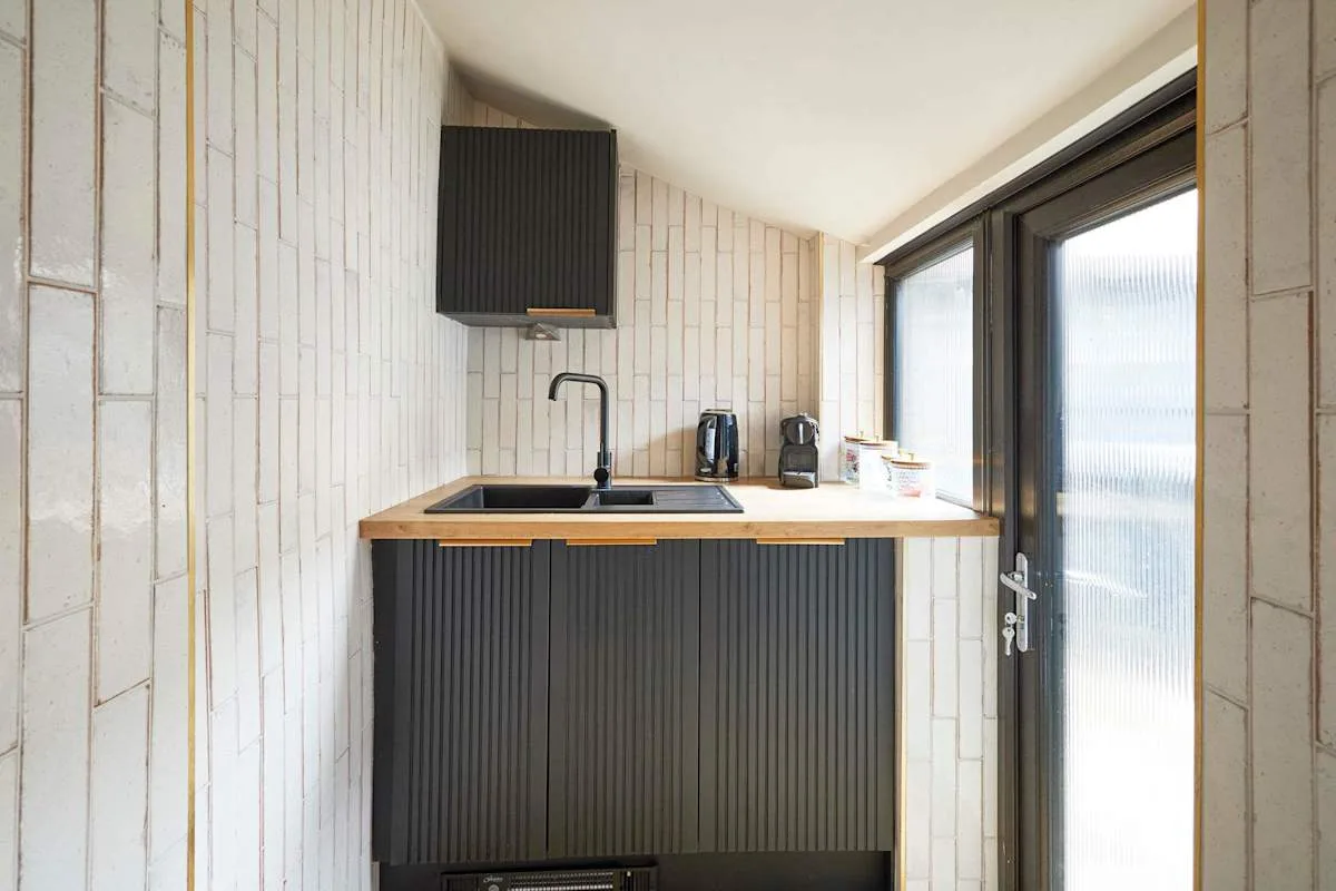 A compact kitchen with dark cabinets and a countertop beside a glazed door.