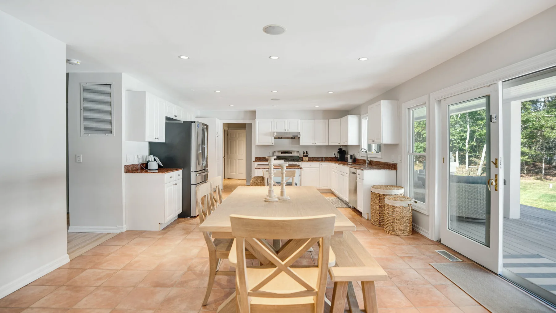 Una luminosa cocina-comedor de planta abierta, con gabinetes blancos y puertas de vidrio.