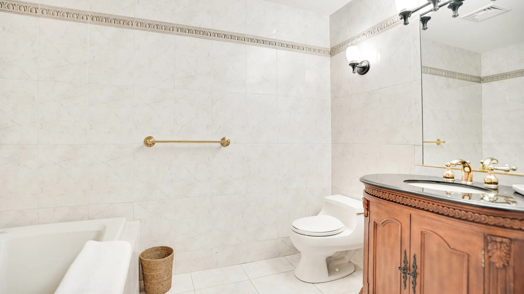 Un baño alicatado con bañera, inodoro y tocador de madera.