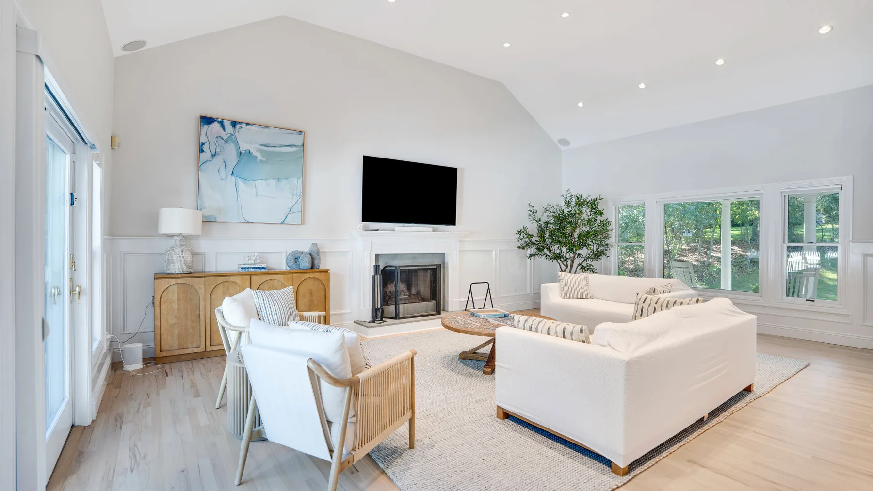 Una sala luminosa con asientos blancos, grandes ventanas y una chimenea.
