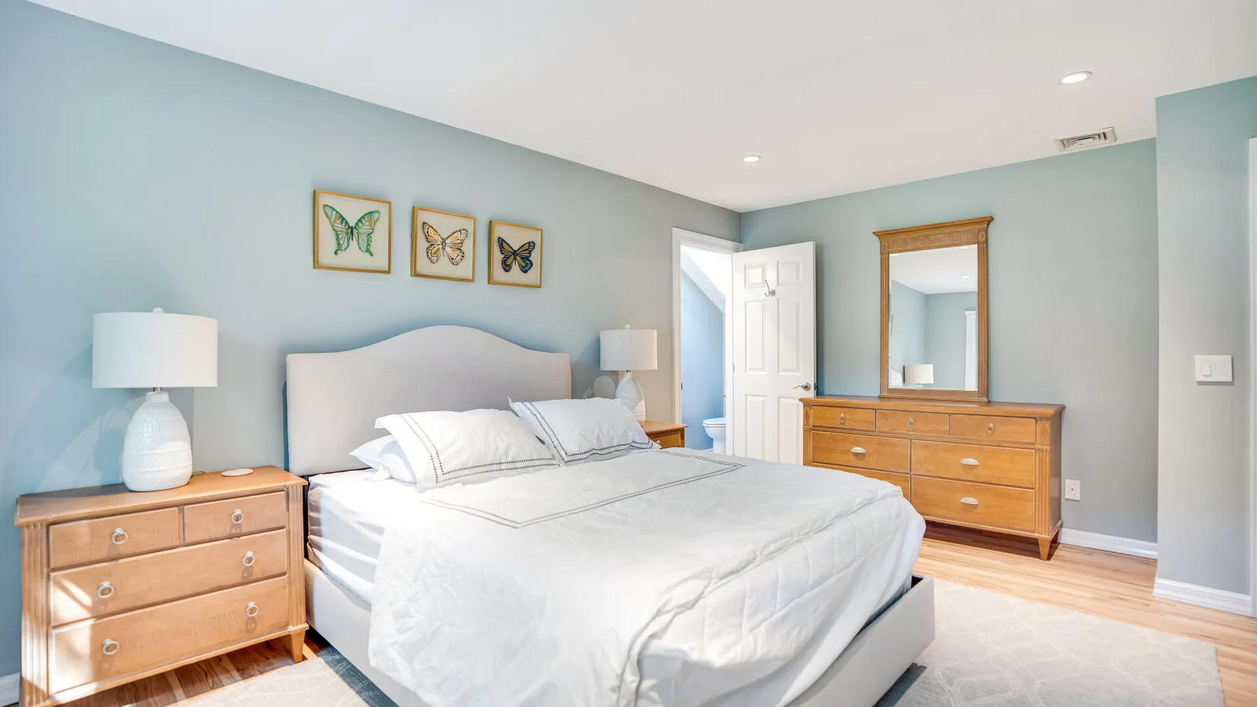Un dormitorio con una cama bien tendida y cómodas de madera.