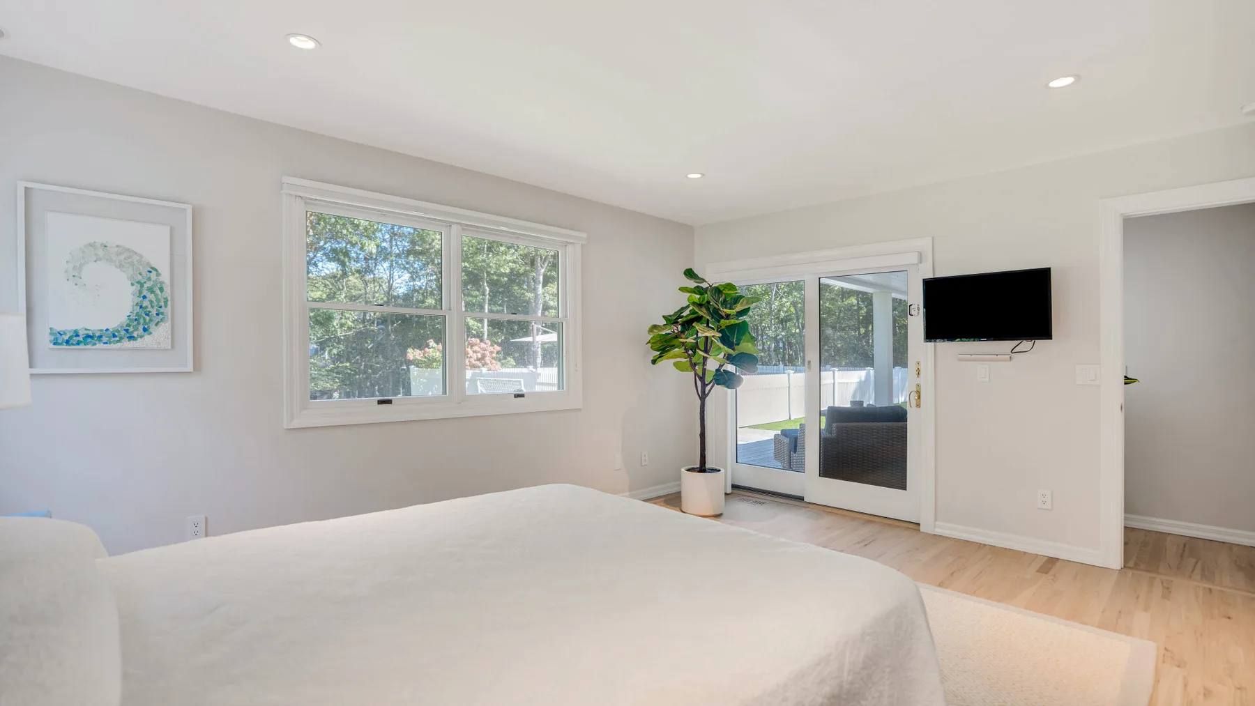 Un dormitorio luminoso con una cama grande, ventanas y puertas corredizas de vidrio.