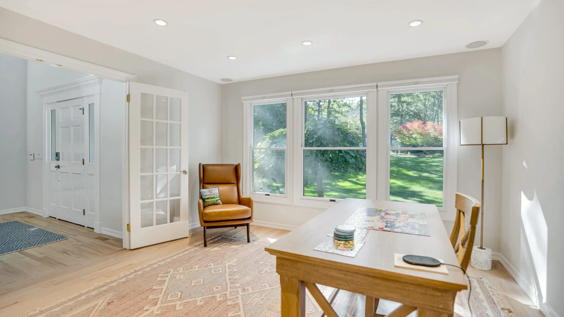 Un comedor luminoso con una mesa de madera junto a grandes ventanas.