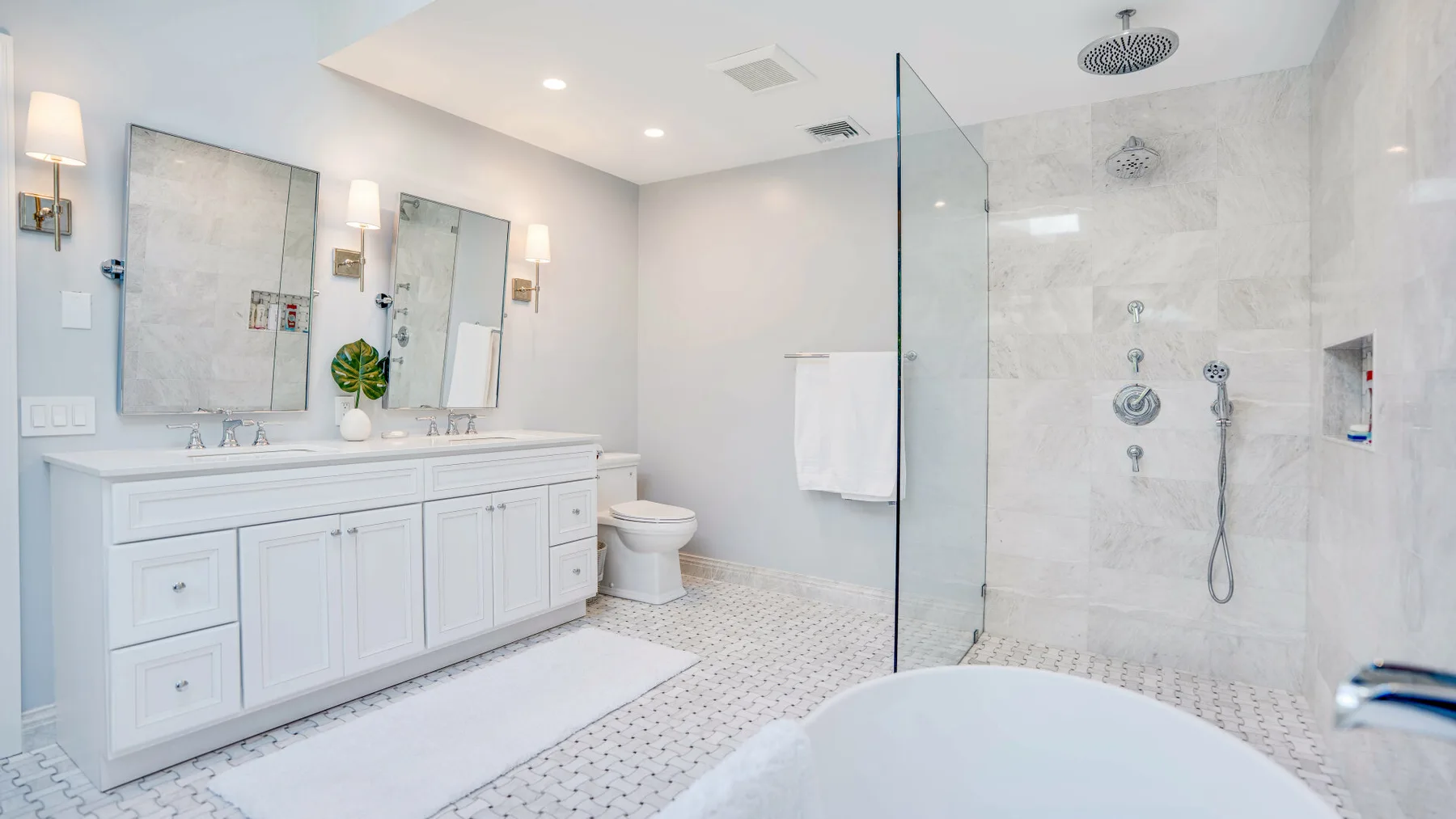 Un baño luminoso tiene un lavabo largo junto a una ducha de vidrio.
