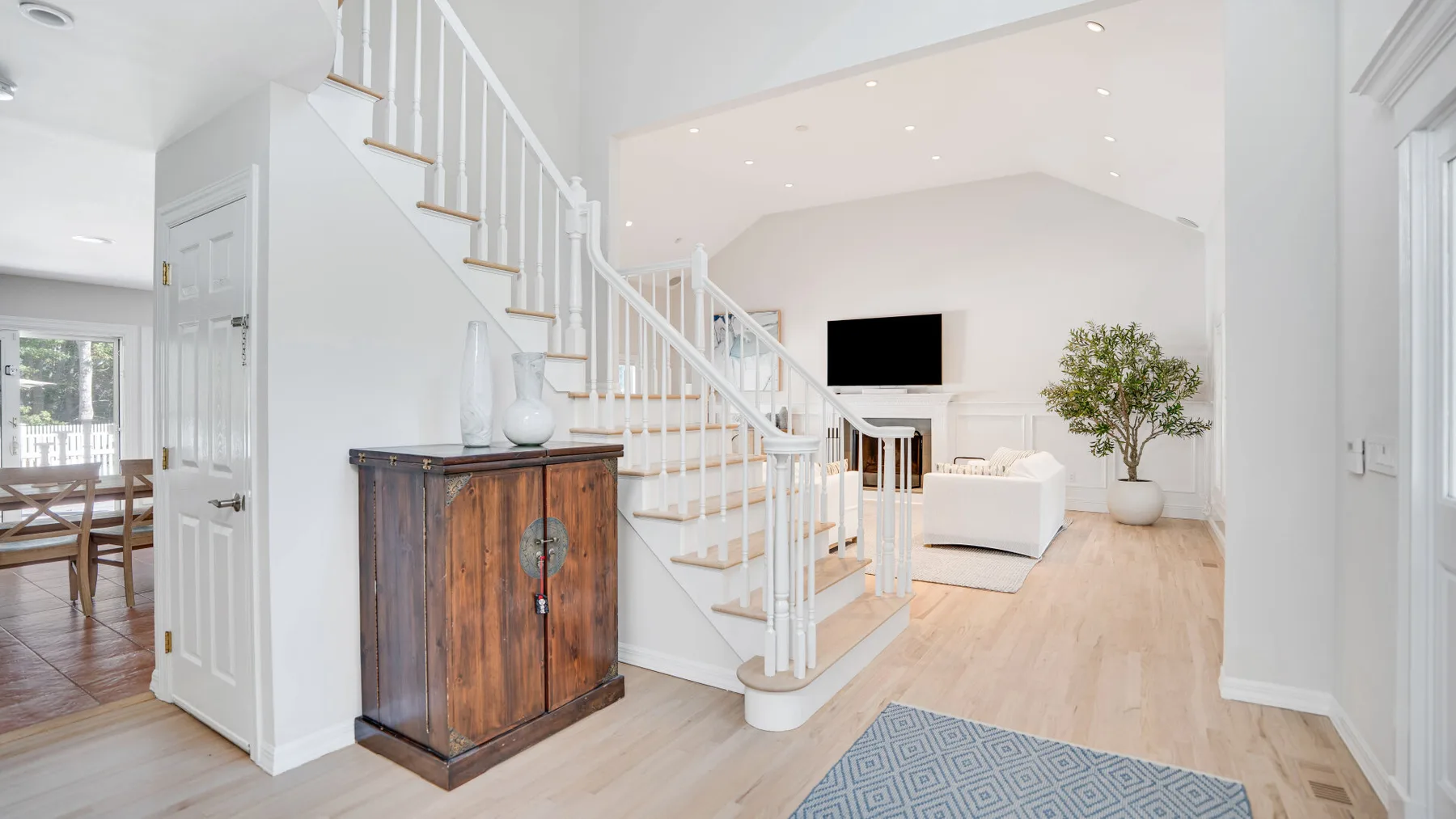 Una sala luminosa y entrada con una escalera y zona de asientos.