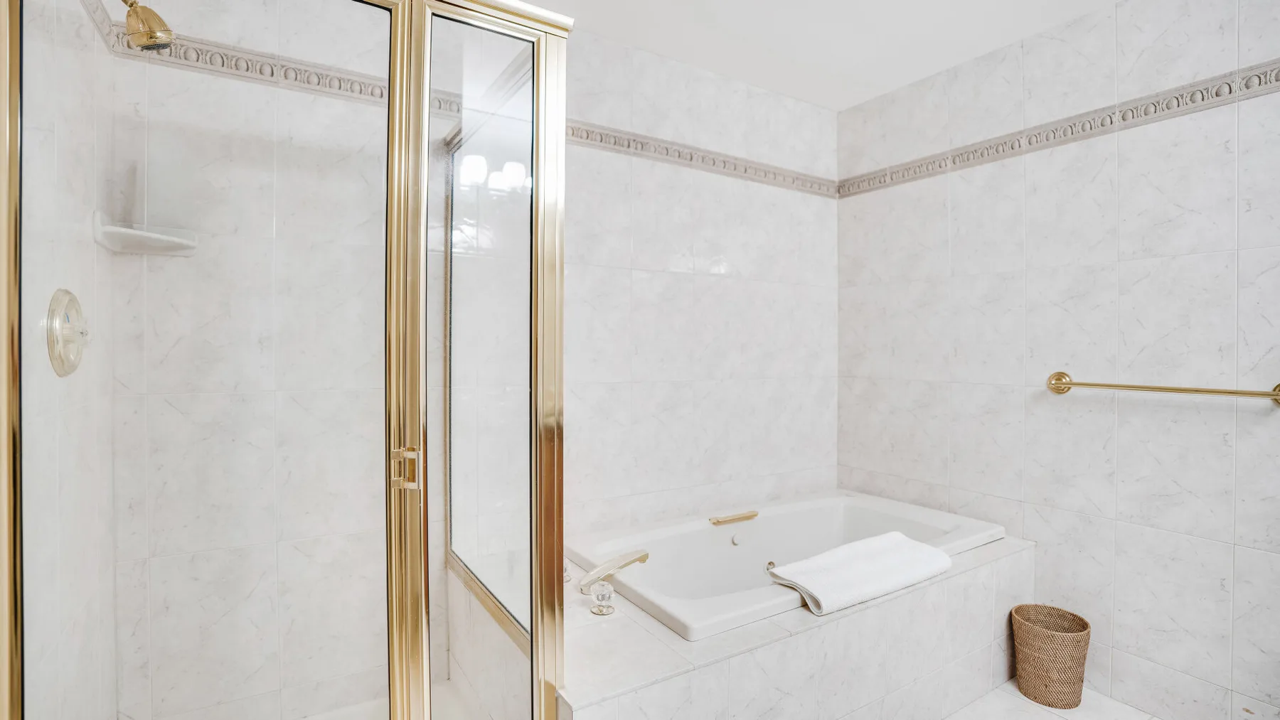 Un baño luminoso con ducha de vidrio y bañera.