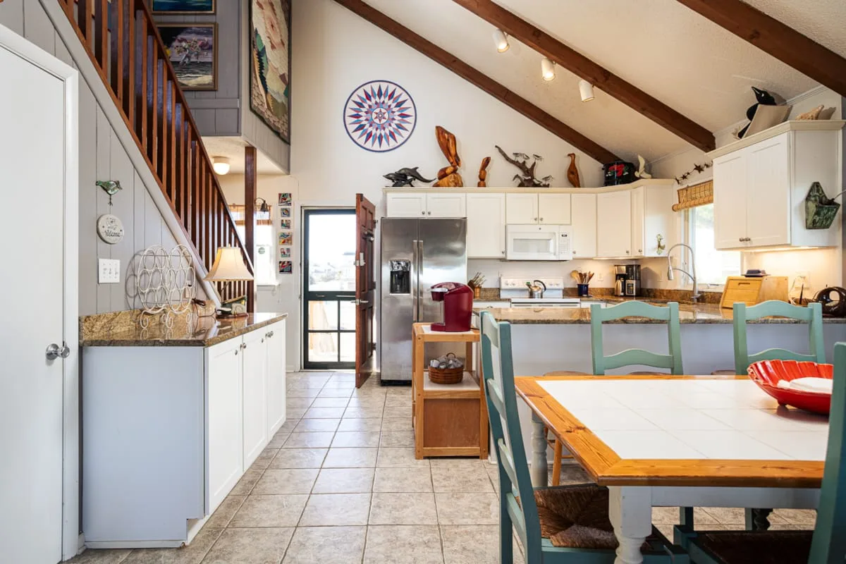 Una cocina luminosa con zona de comedor, una barra larga y una mesa.