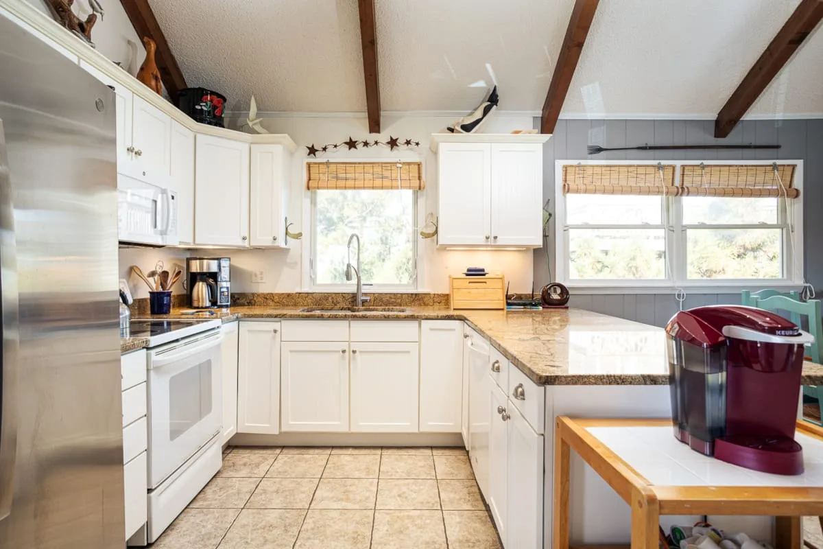 Una cocina luminosa con gabinetes blancos y una isla central.