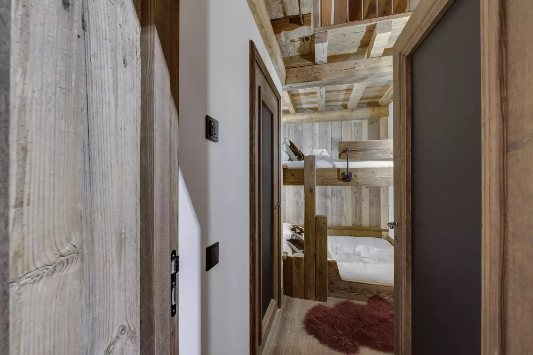 A rustic hallway opens onto a bathroom with a bathtub and wooden beams.