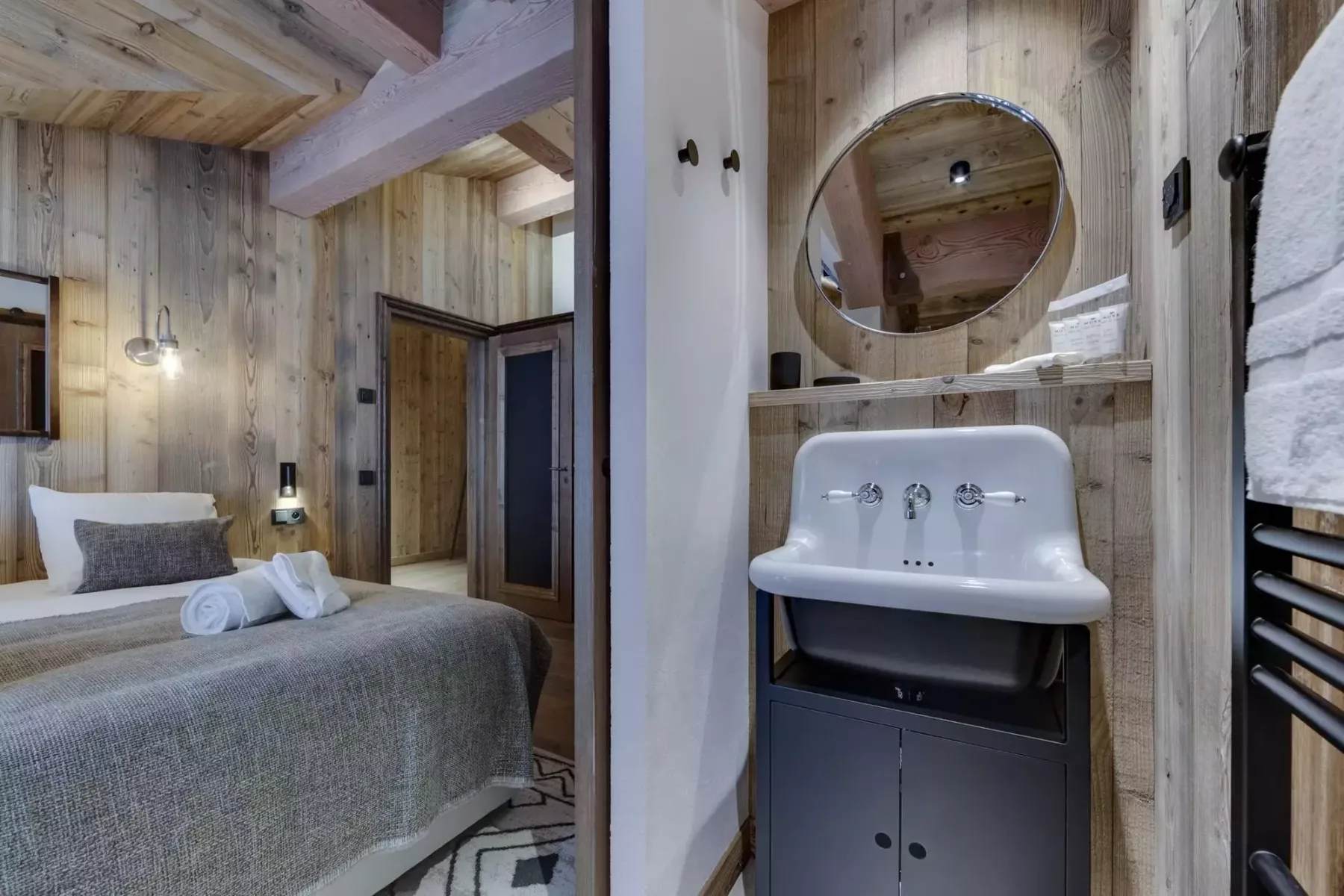 A wood-paneled bedroom with a bed beside a compact sink vanity.
