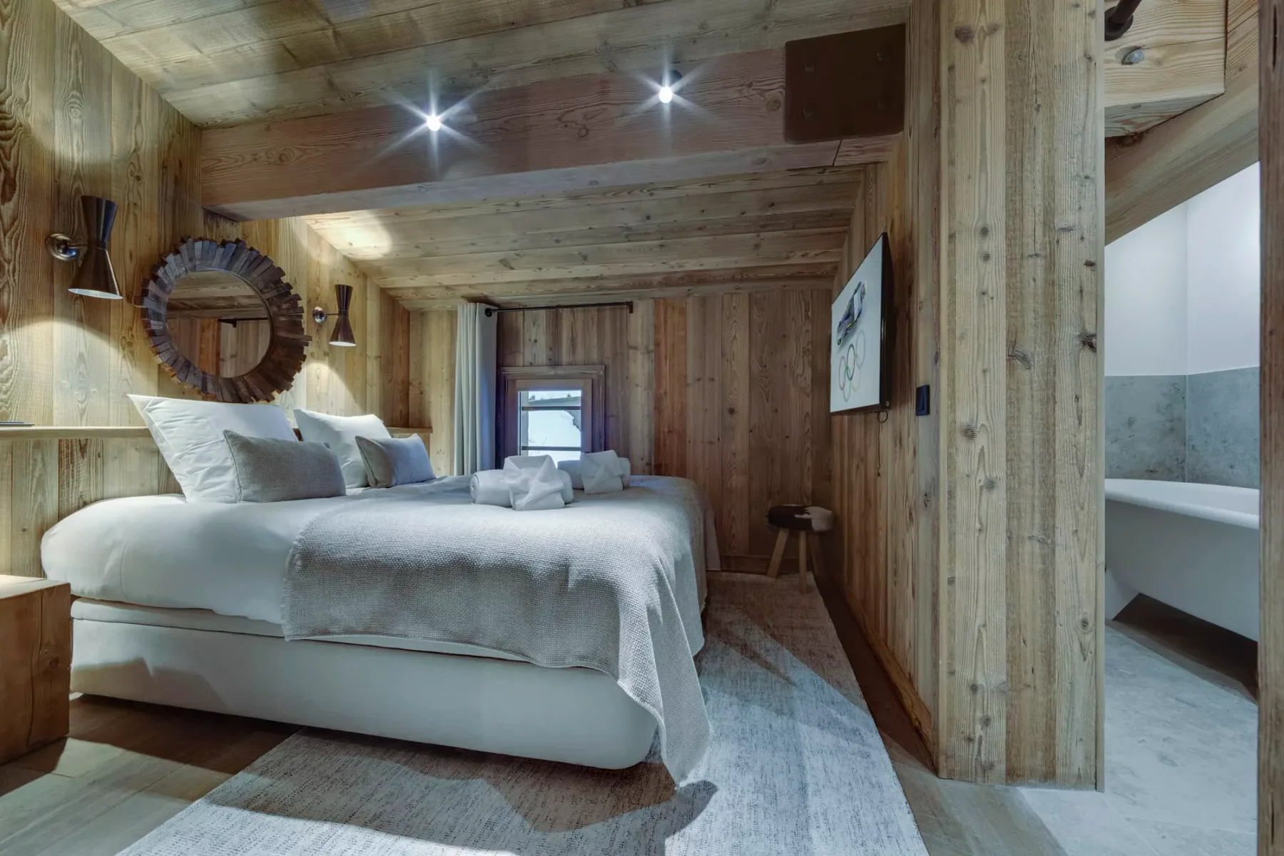 A wood-paneled bedroom with a large bed and an adjoining bathroom.