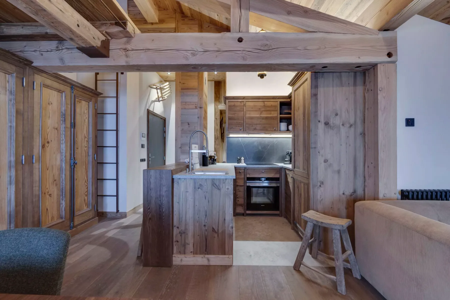 A rustic kitchen with a wooden island, cabinets, and an adjoining seating area.