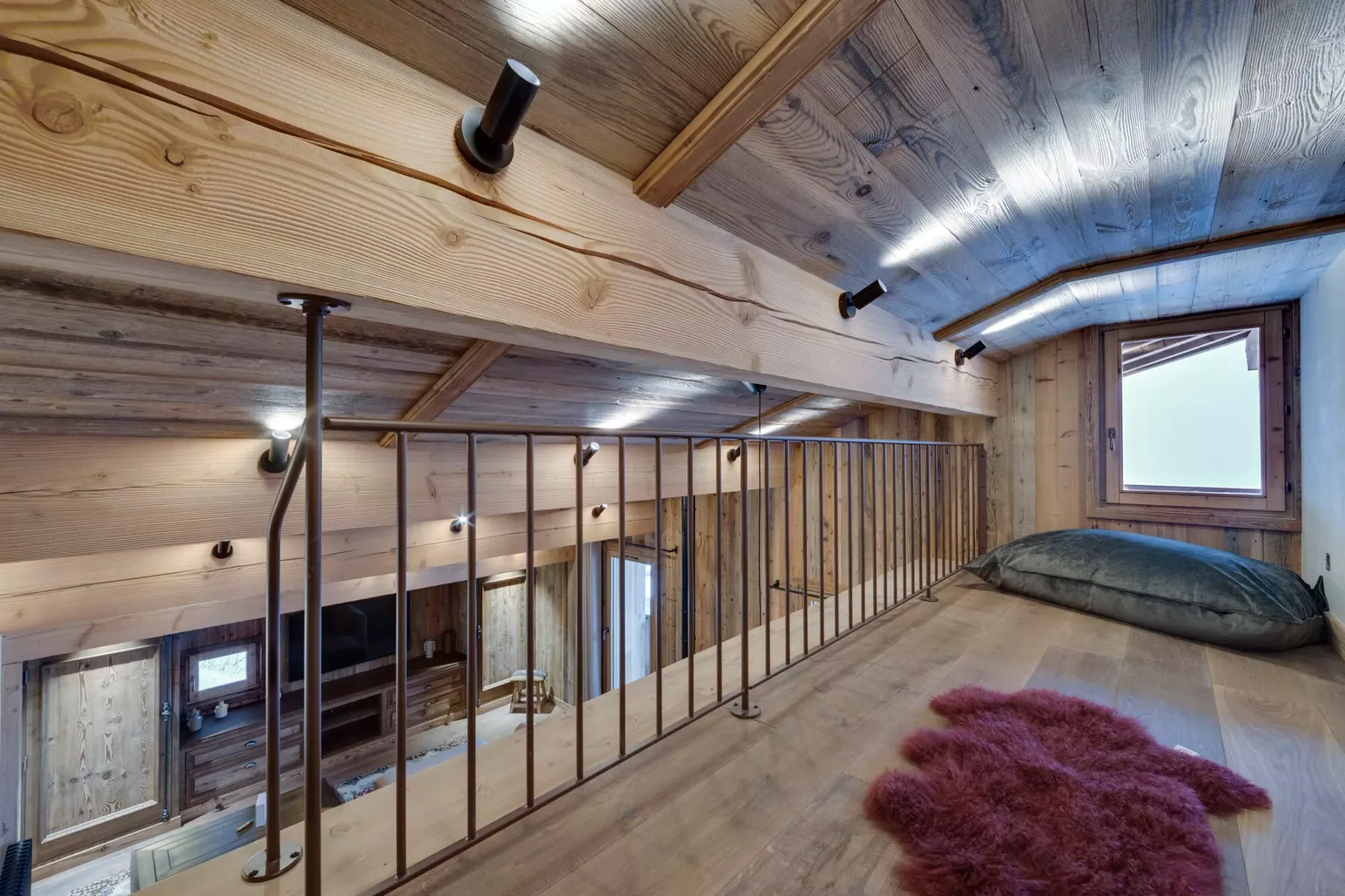 A wooden loft space with a railing and a window.