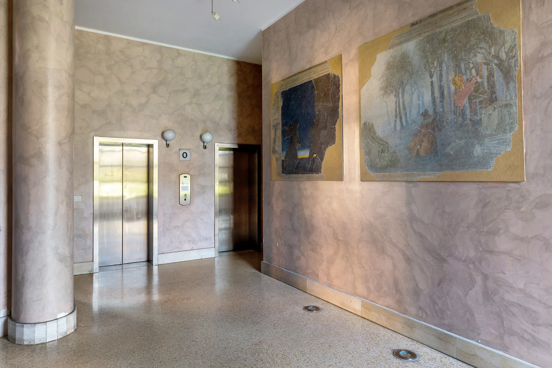 Un vestíbulo de ascensores con dos puertas y obras enmarcadas en la pared.