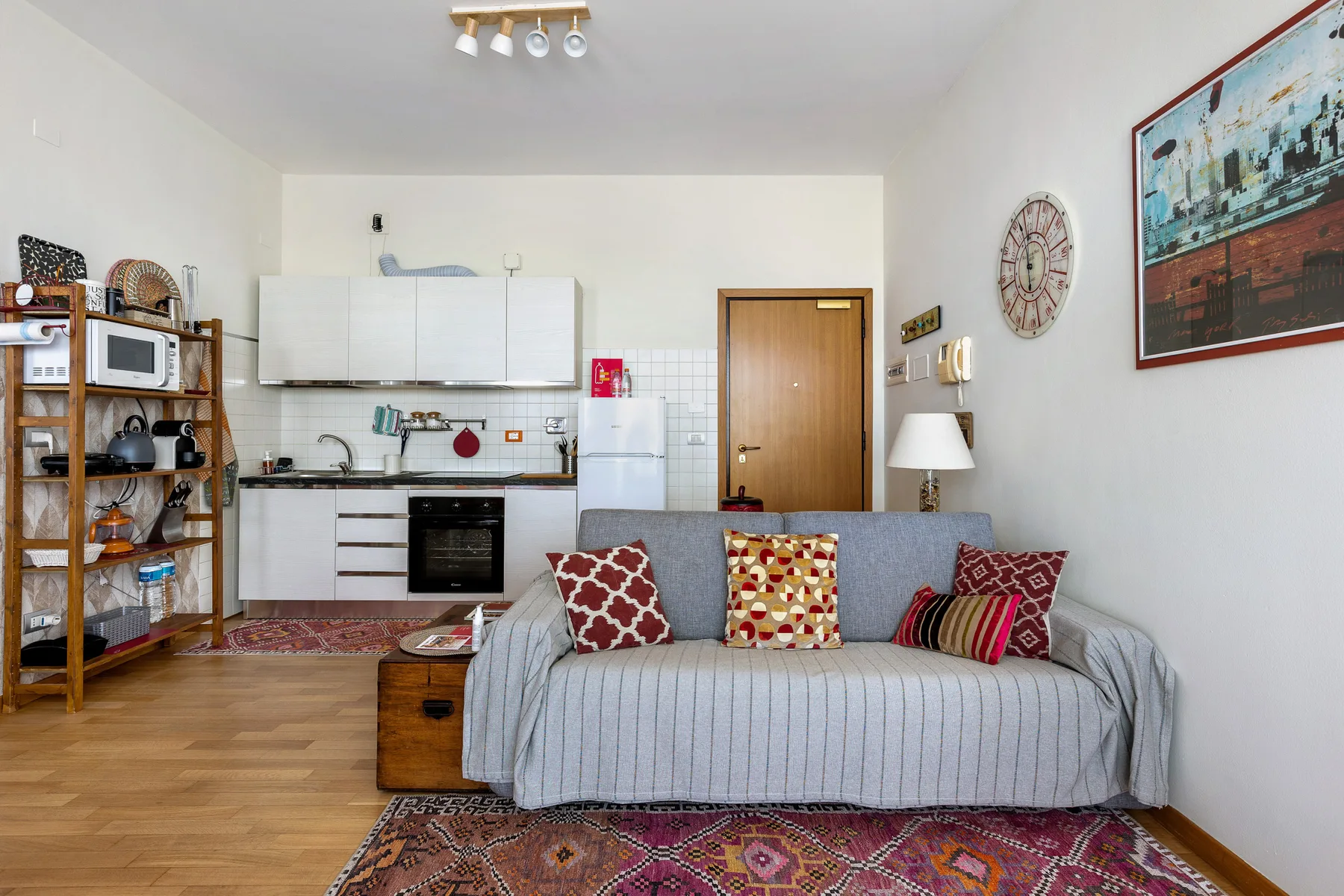 Una sala de estar con un sofá gris y una cocina abierta detrás.