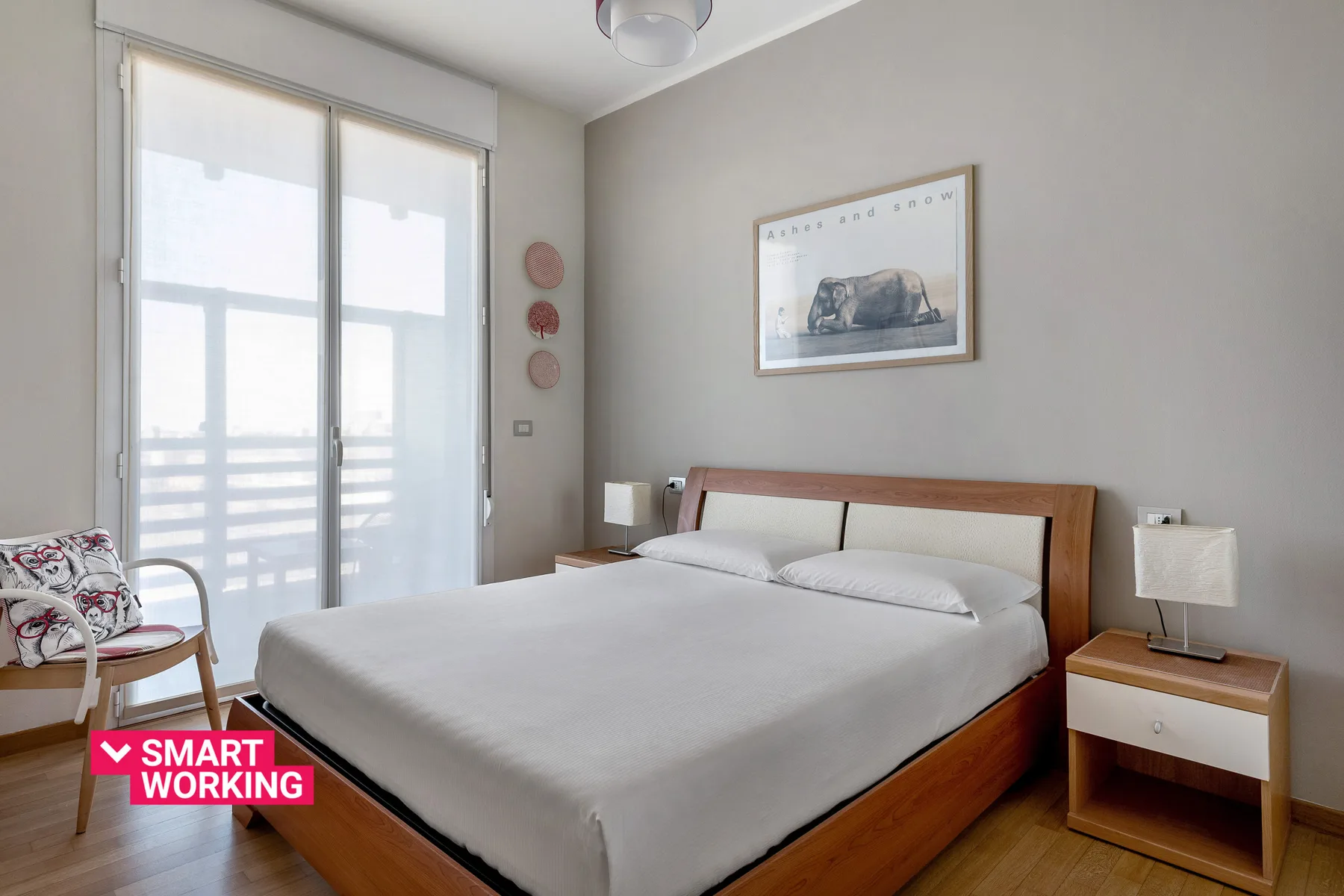 Un dormitorio con una cama grande, arte enmarcado y puertas de vidrio.