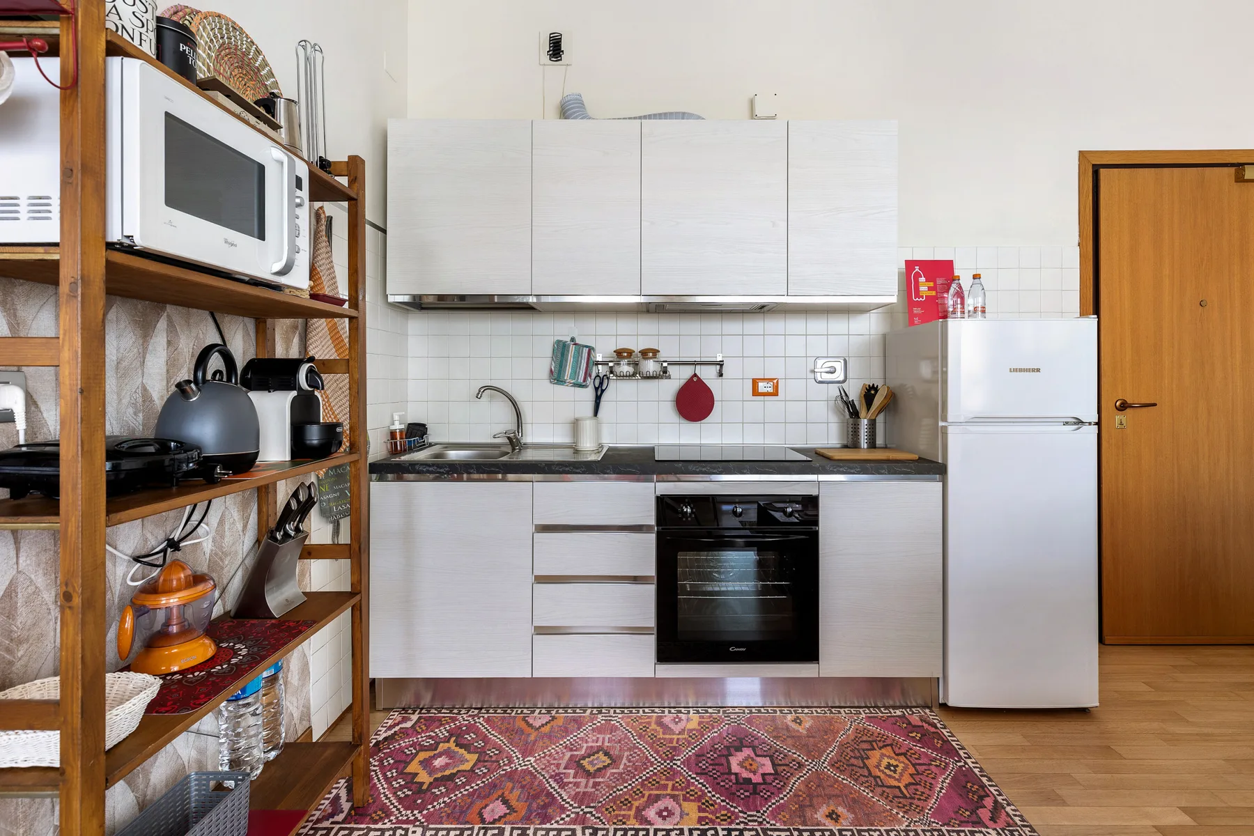 Una cocina con armarios blancos, un refrigerador y un horno.