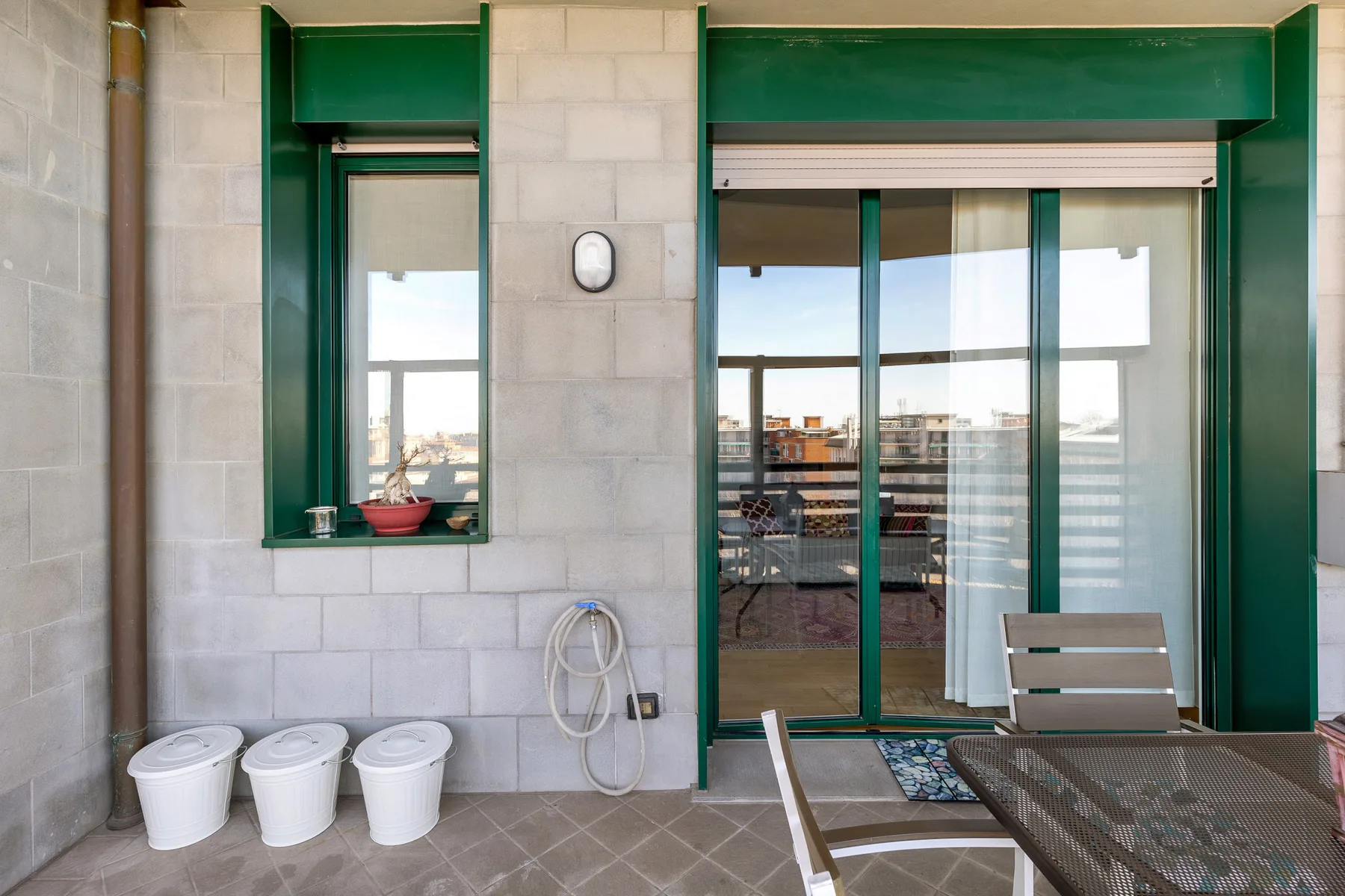 Una terraza en la azotea con puertas corredizas de vidrio y asientos al aire libre.