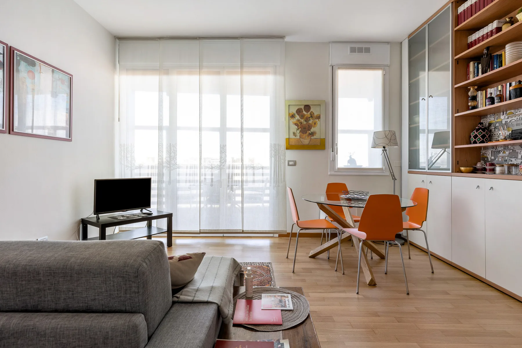 Una luminosa sala de estar y comedor con asientos, un televisor y una mesa de comedor.