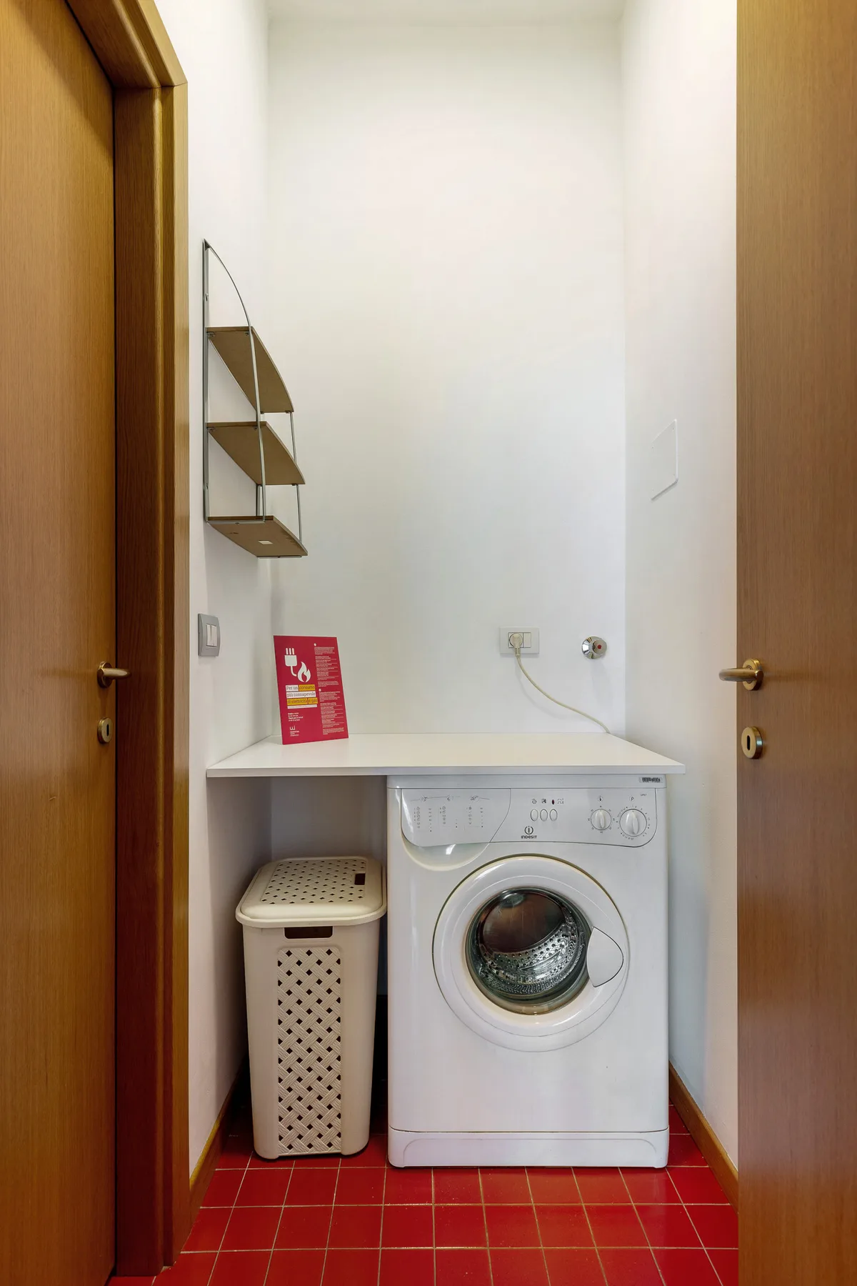 Una zona de lavandería con una lavadora de carga frontal y un cesto para ropa.