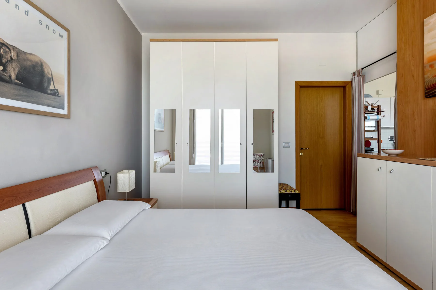 Dormitorio con cama, armario con espejo y puerta de madera.