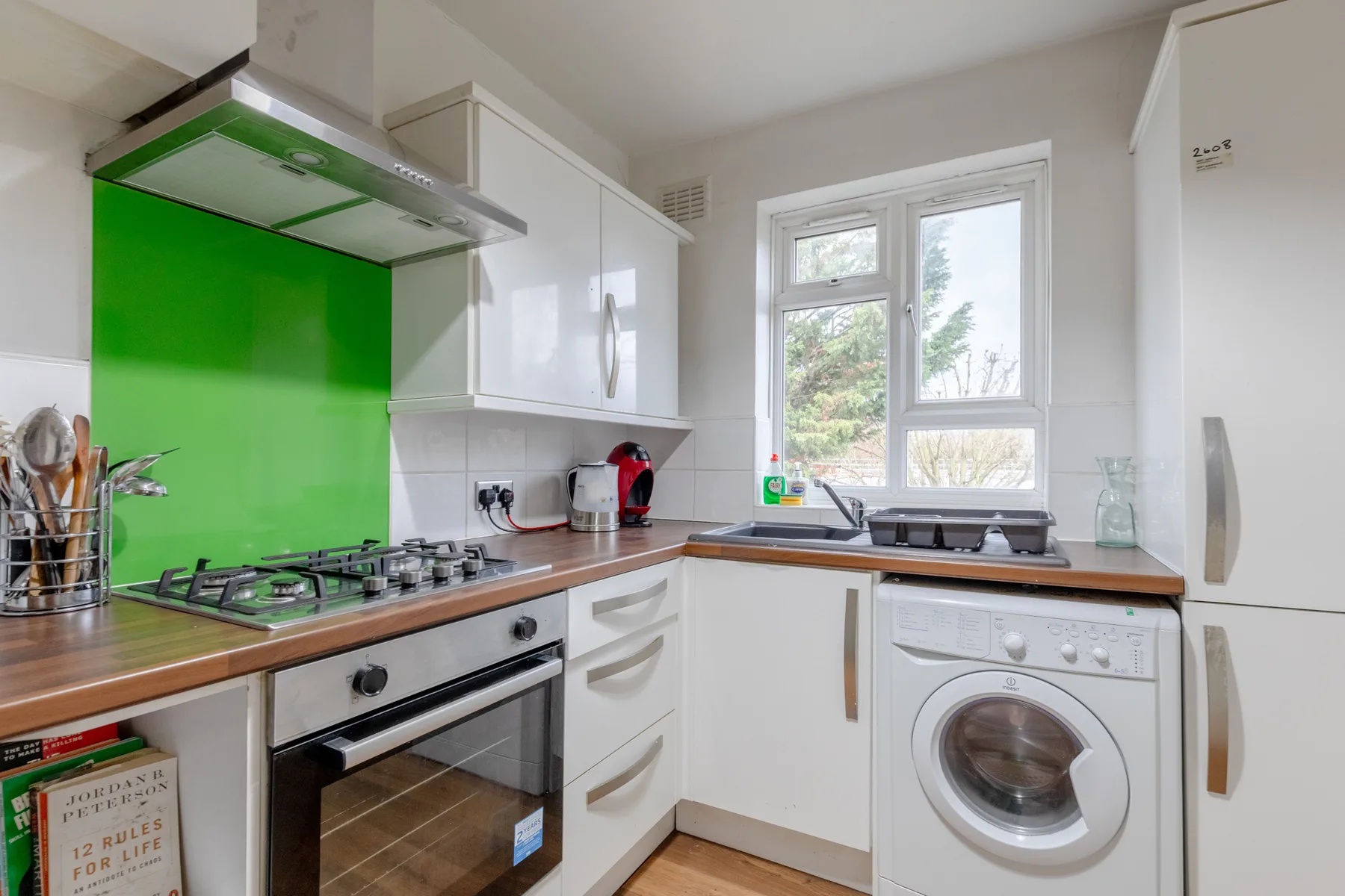 A bright kitchen with a gas cooktop, sink, and front-loading washing machine.