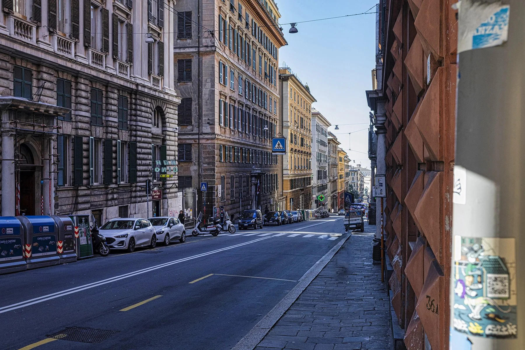 Una calle urbana flanqueada por edificios altos y coches estacionados.