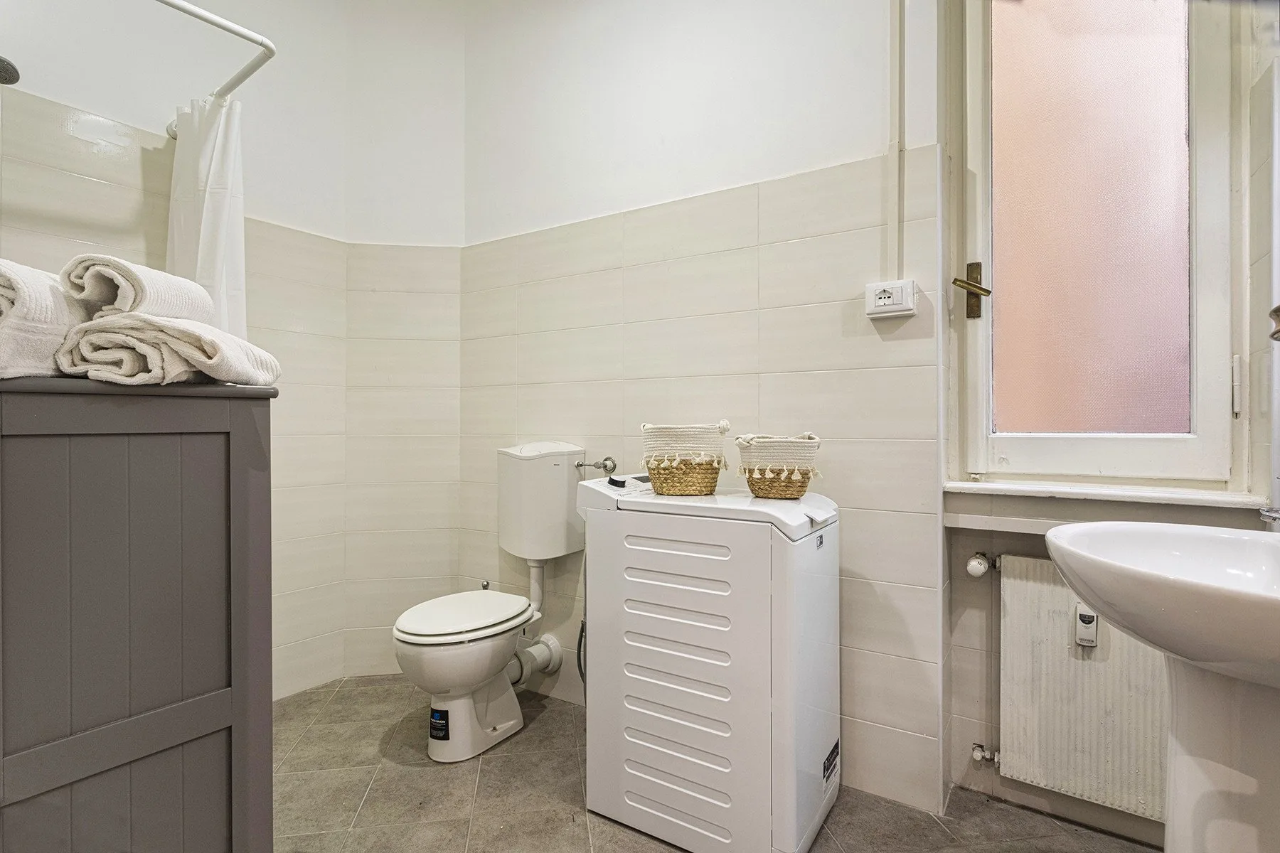 Un baño alicatado con inodoro, mueble de lavabo y cortina de ducha.