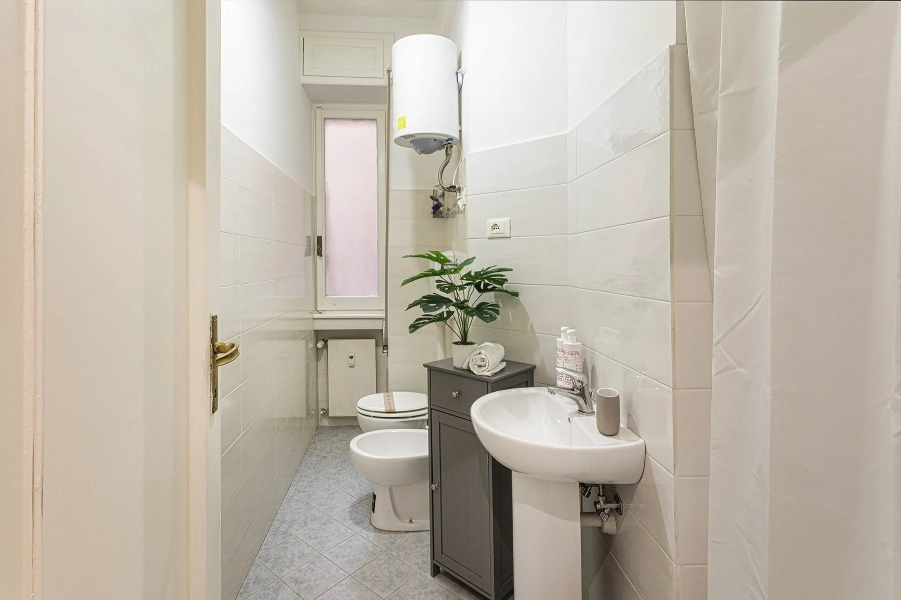 Un baño compacto con lavabo, inodoro y cortina de ducha.