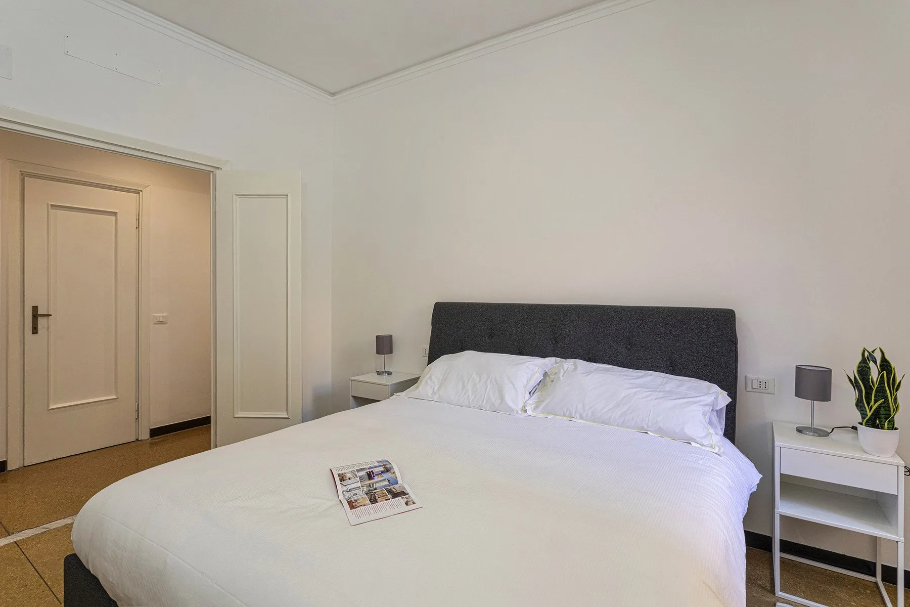 Un dormitorio con una cama grande, ropa de cama blanca y mesitas de noche.