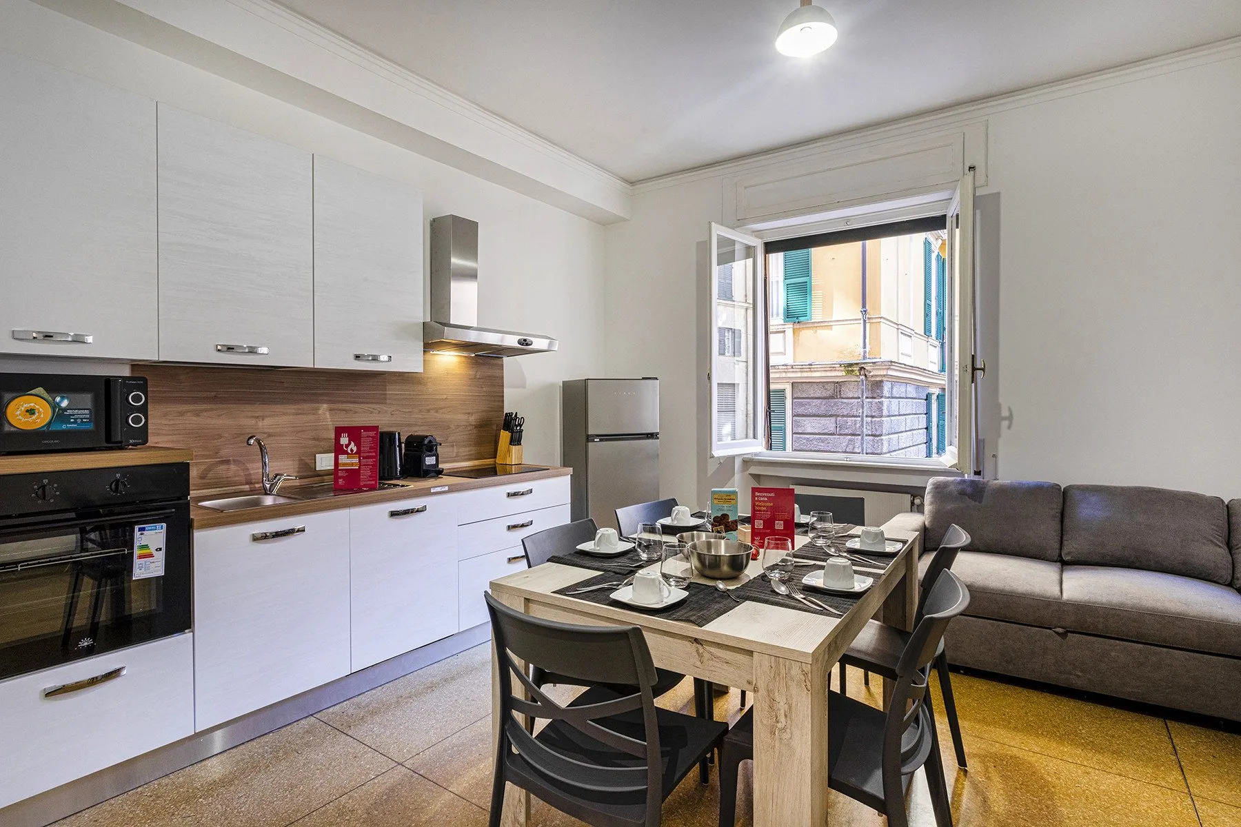 A bright kitchen and dining area with a table set beside an open window.