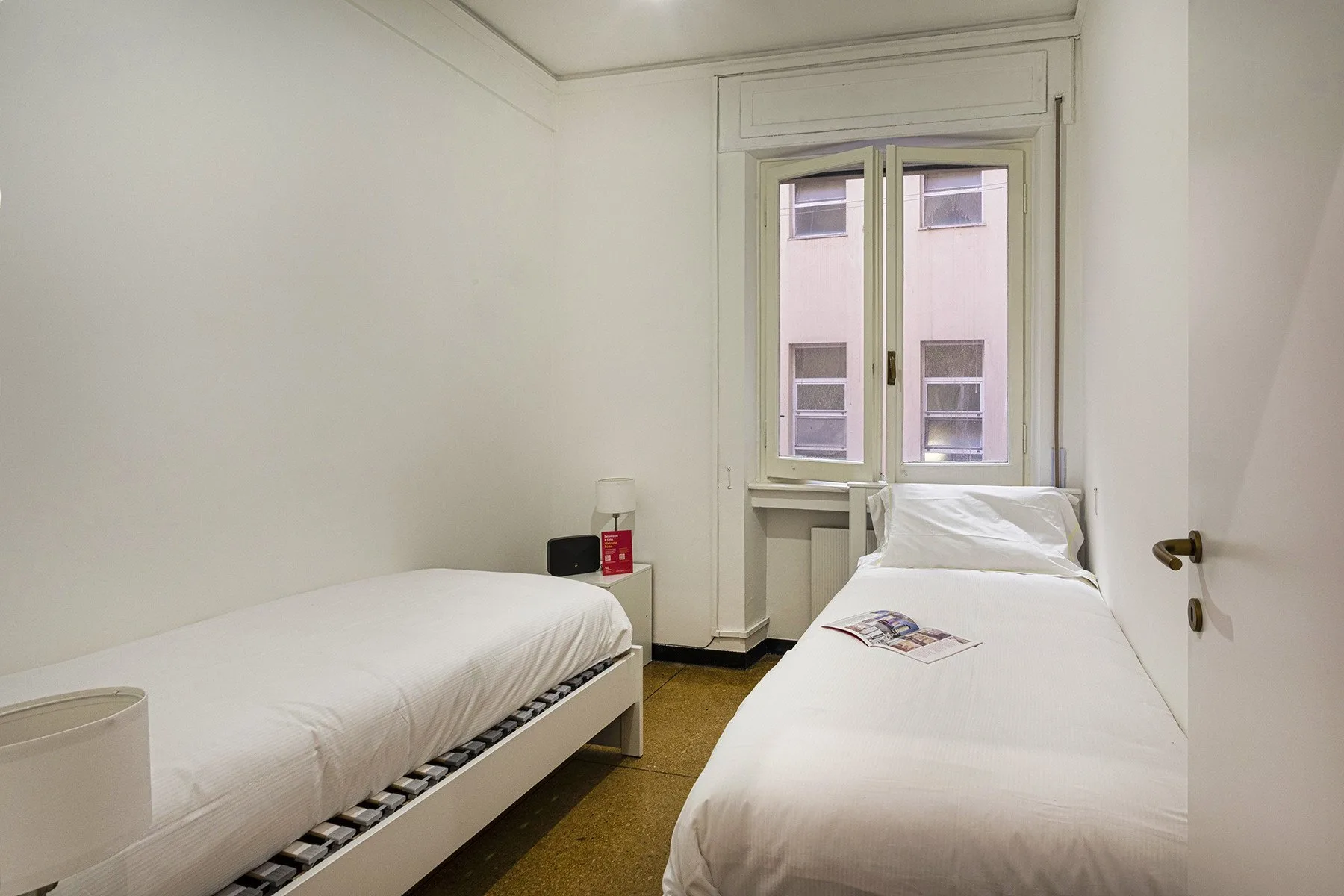 A bedroom with two single beds and a window.