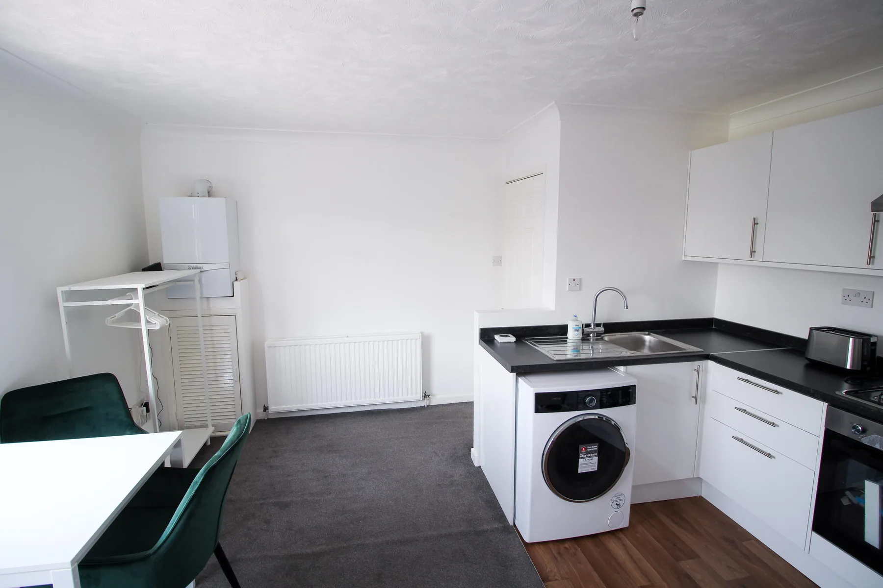 A compact kitchen with a sink, washing machine, and dining table.