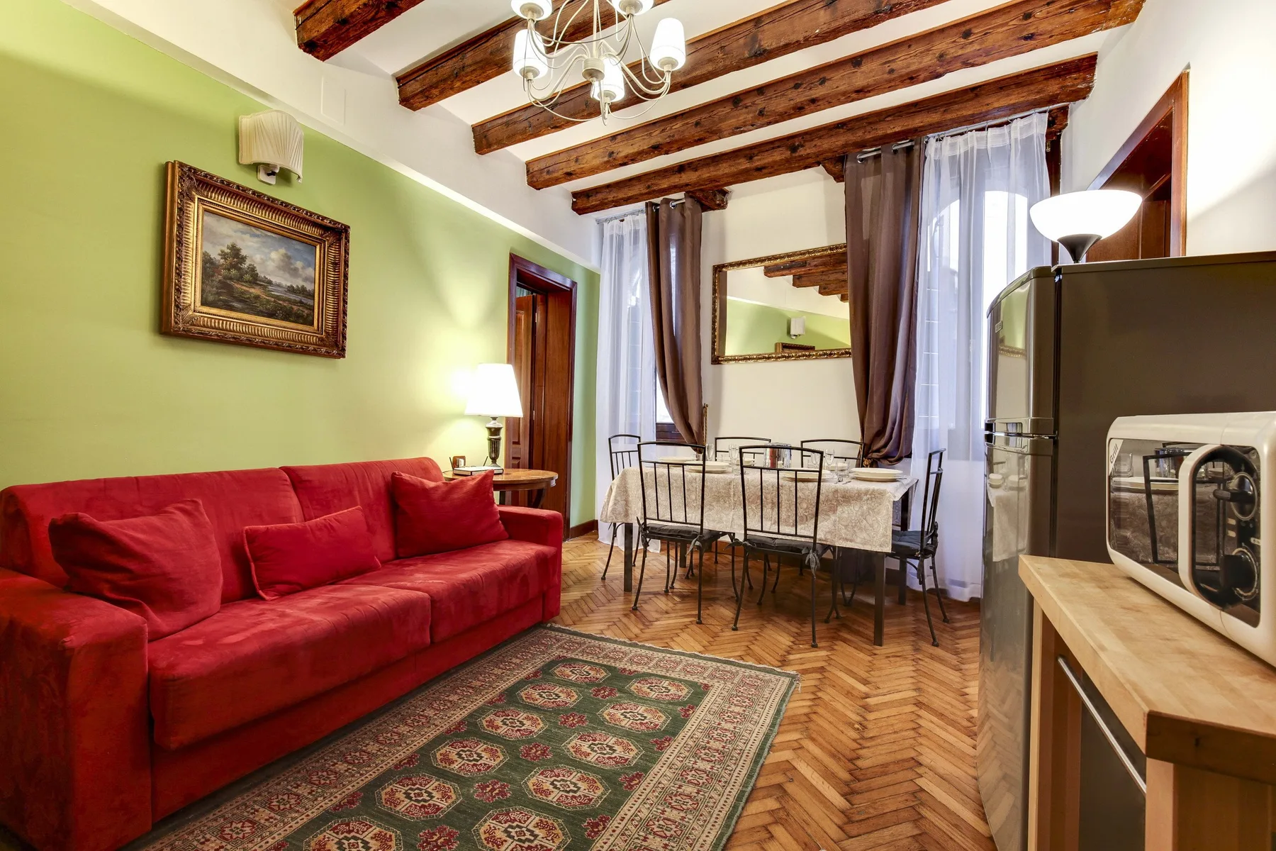 Una sala de estar y comedor con asientos rojos, una mesa y vigas a la vista.