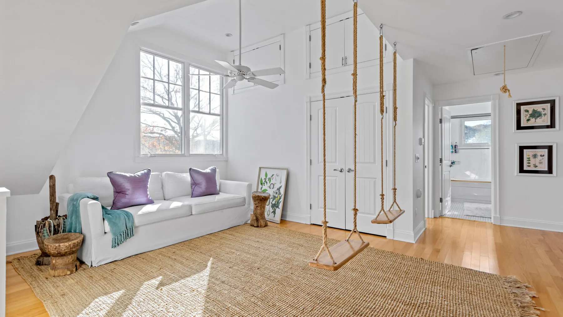 Una sala luminosa con asientos blancos y columpios colgantes.