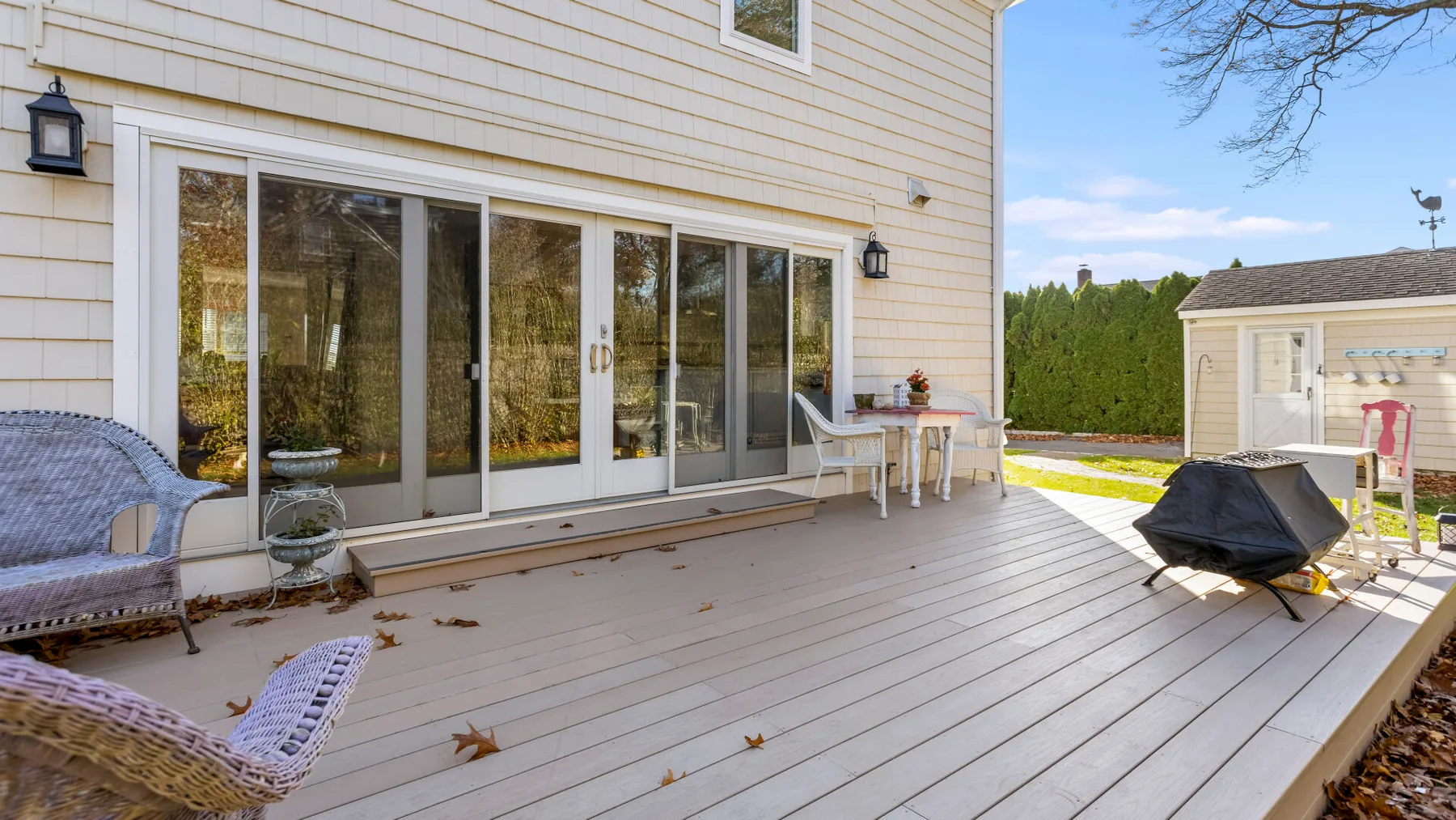 Una terraza exterior junto a una casa, con puertas corredizas de vidrio y asientos de patio.