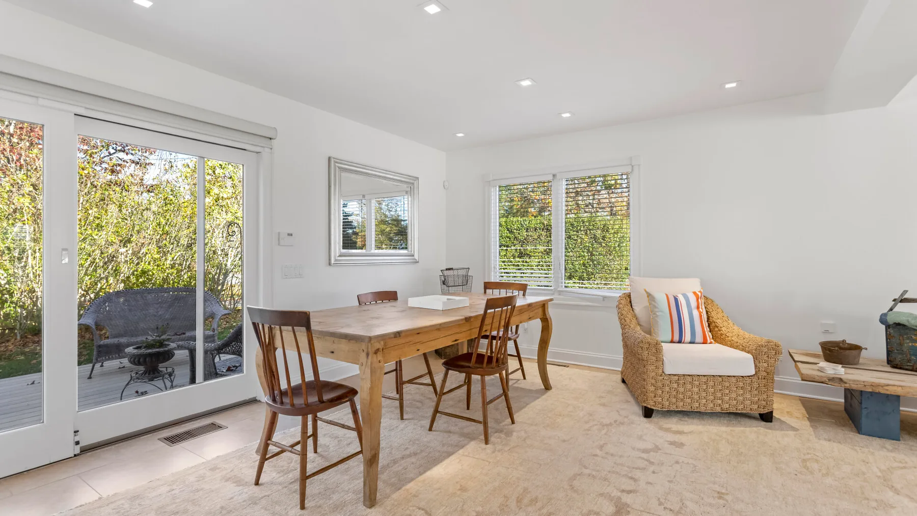 Un comedor luminoso con una mesa de madera y asientos junto a grandes ventanas.