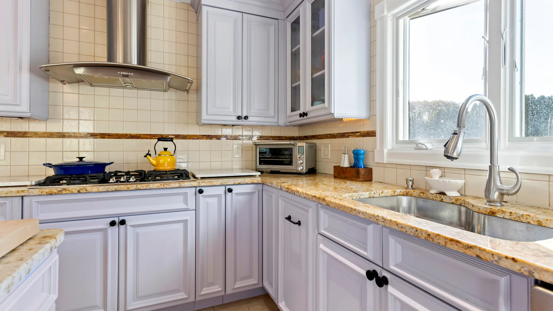 Una cocina luminosa con gabinetes blancos, una encimera y una ventana.