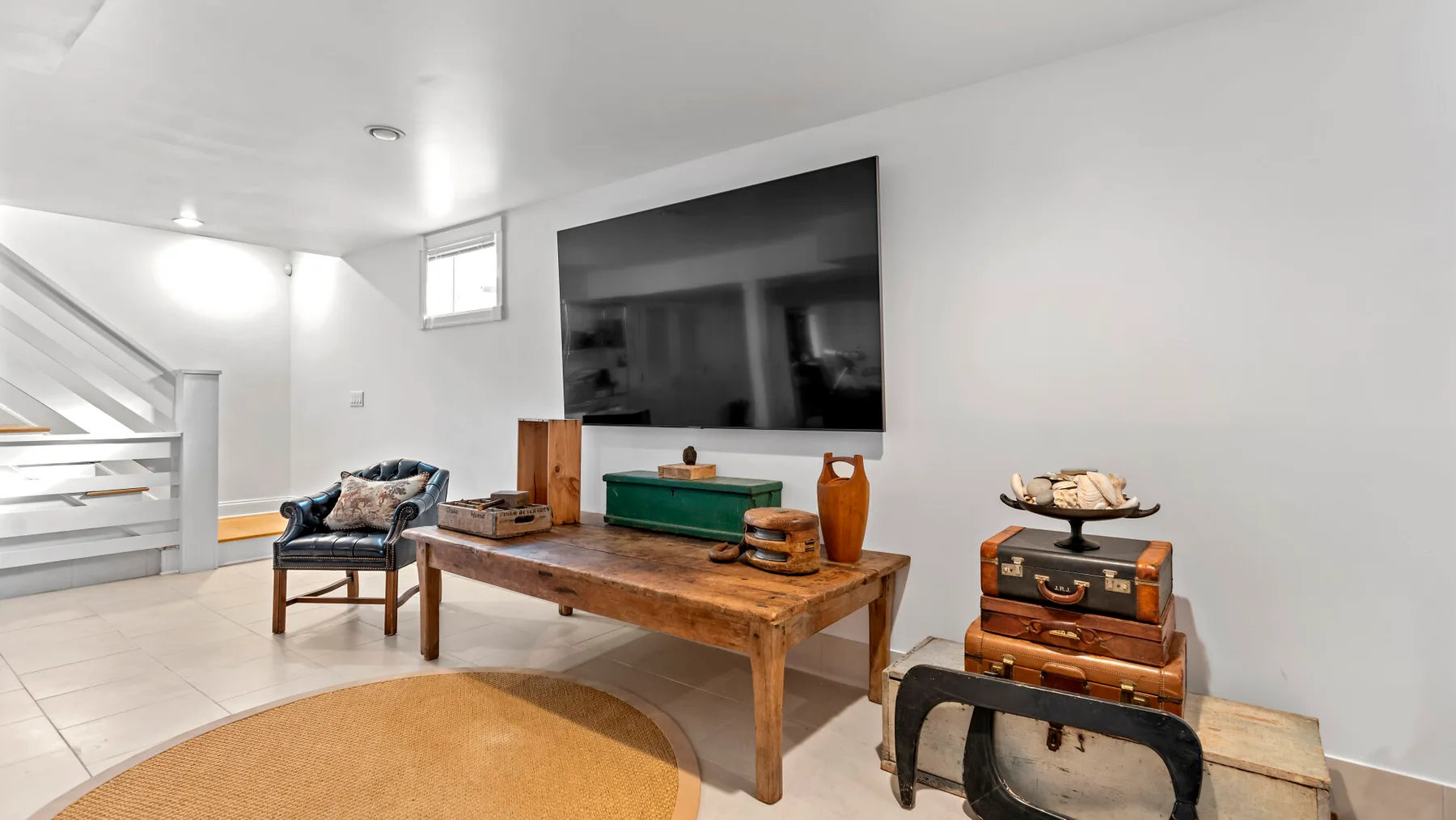 Una sala luminosa con asientos bajos, una mesa de centro de madera y un televisor en la pared.
