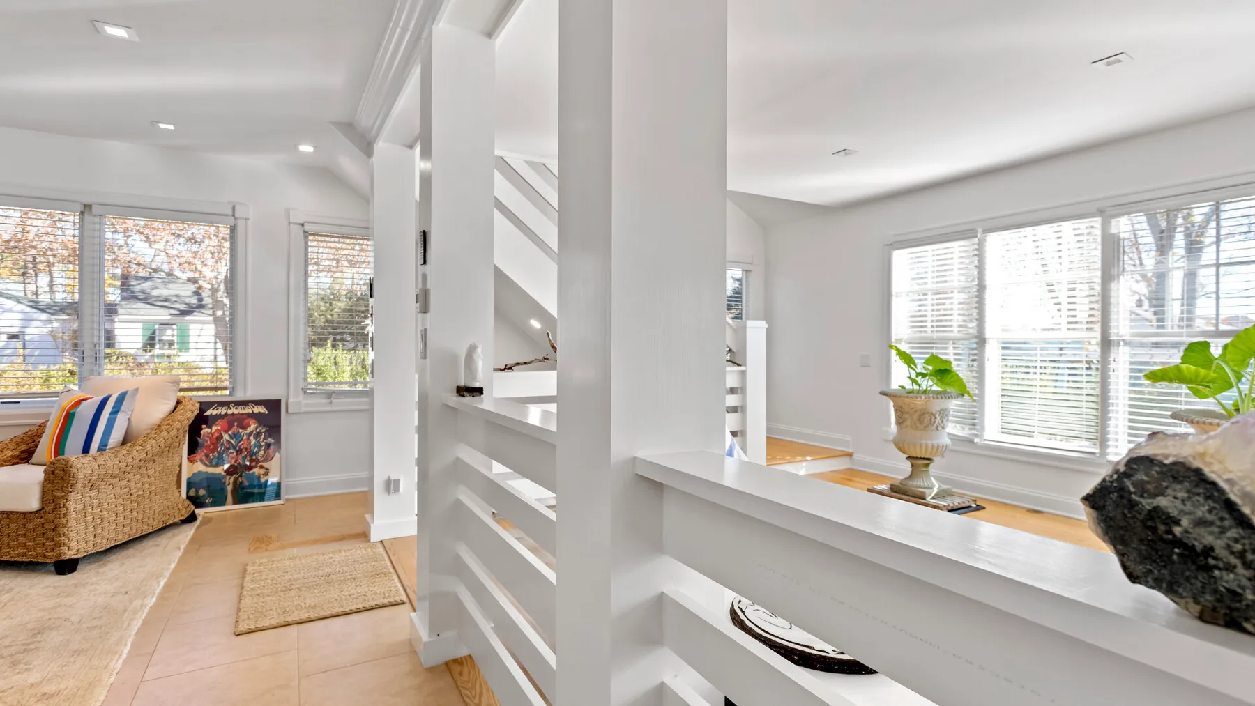 Una sala luminosa con ventanas grandes y un asiento tejido.