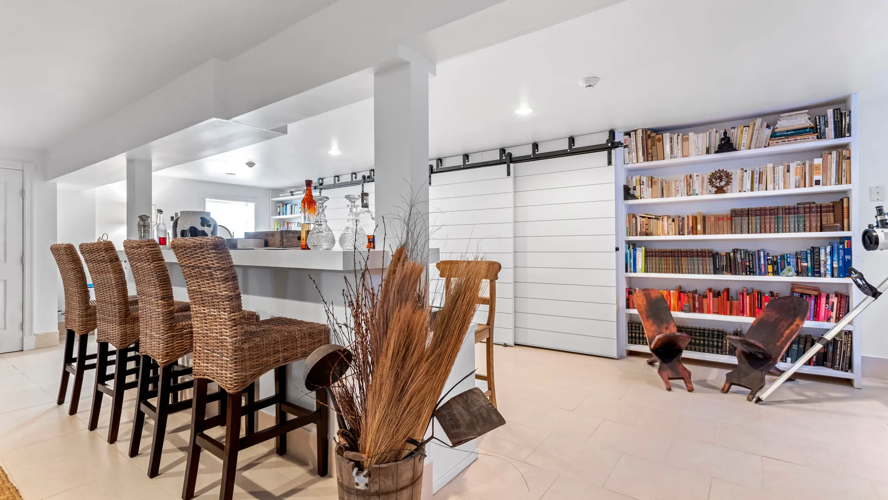 Comedor de espacio abierto con asientos tejidos junto a una isla de cocina y estanterías.