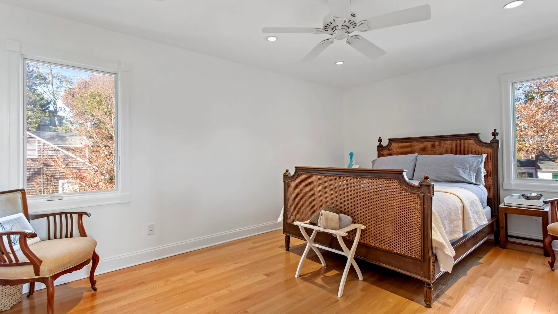 Un dormitorio luminoso con una cama de madera y ventanas grandes.