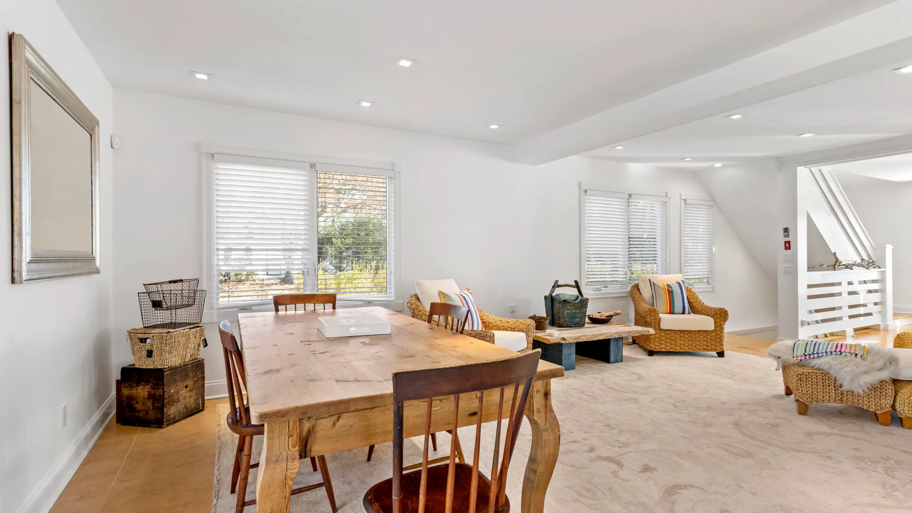 Un comedor y sala de estar luminosos, con una mesa de madera y asientos junto a las ventanas.