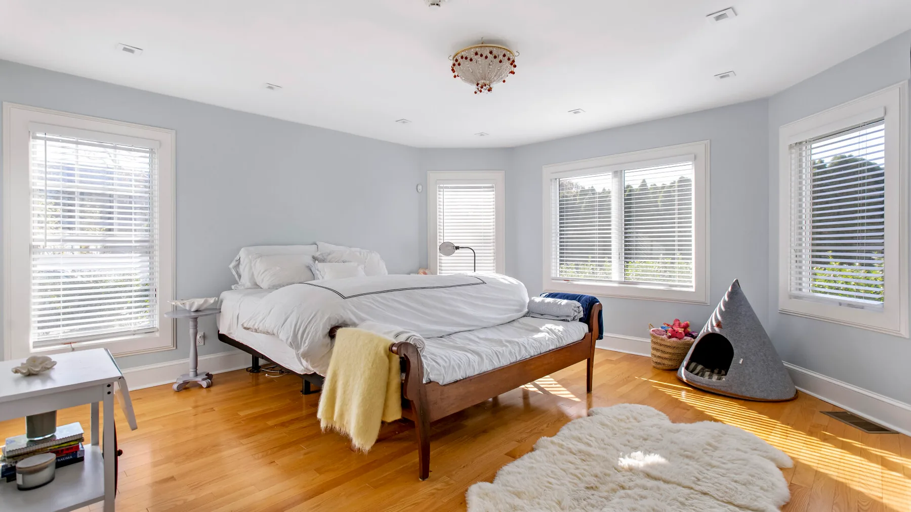 Un dormitorio luminoso con una cama, varias ventanas y una alfombra suave.