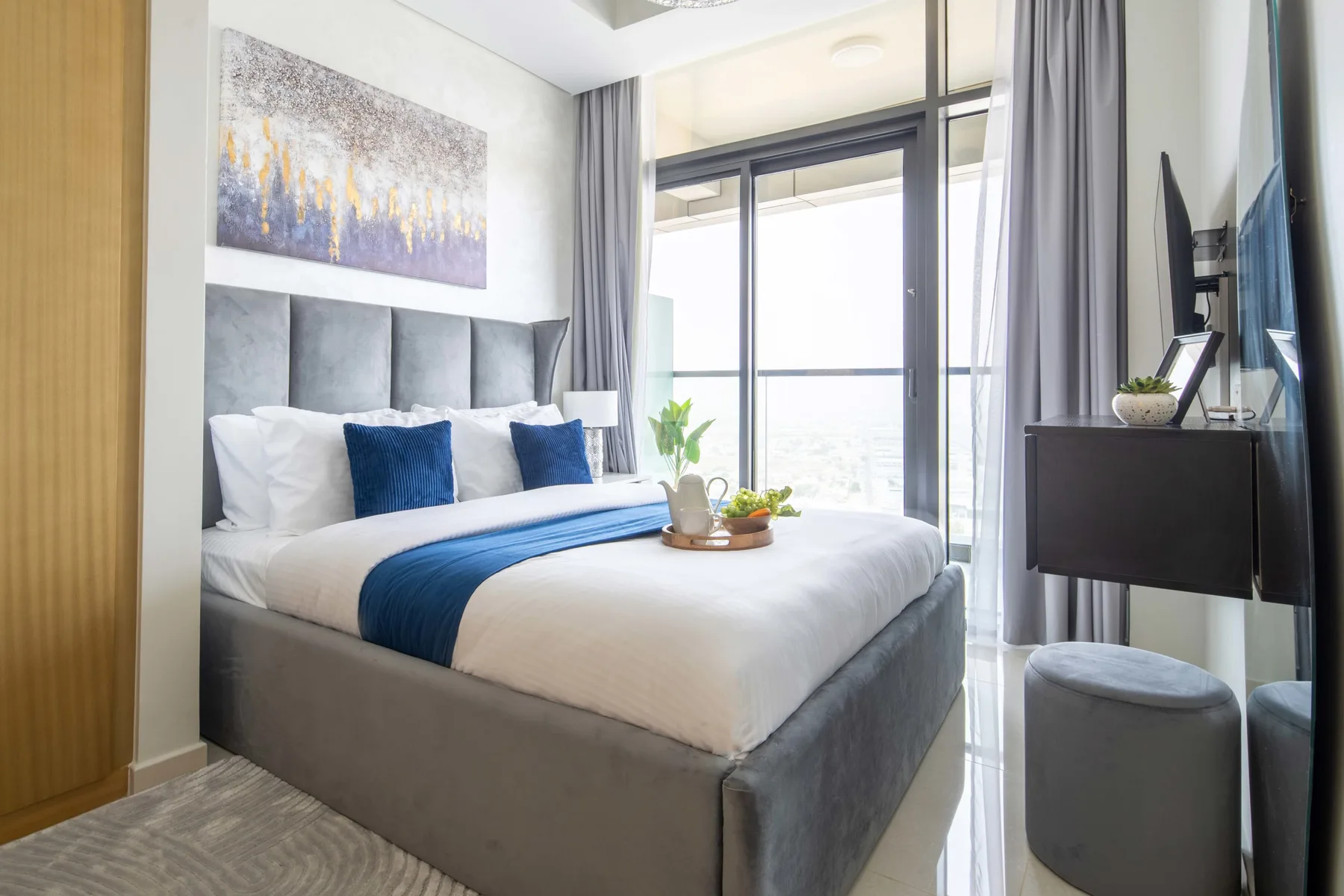A bedroom with a neatly made bed and sliding glass doors opening onto a balcony.