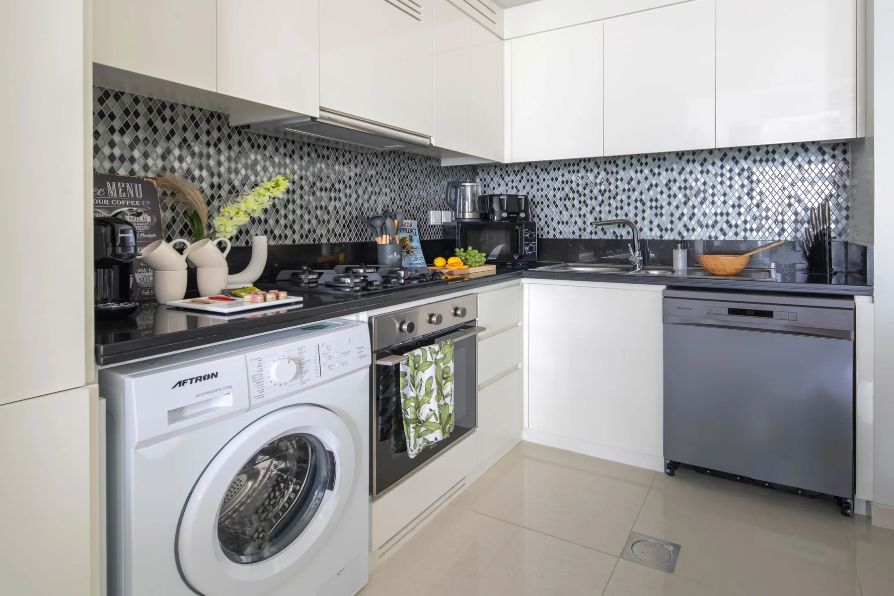 A bright kitchen with white cabinets, dark countertops, and a washing machine.