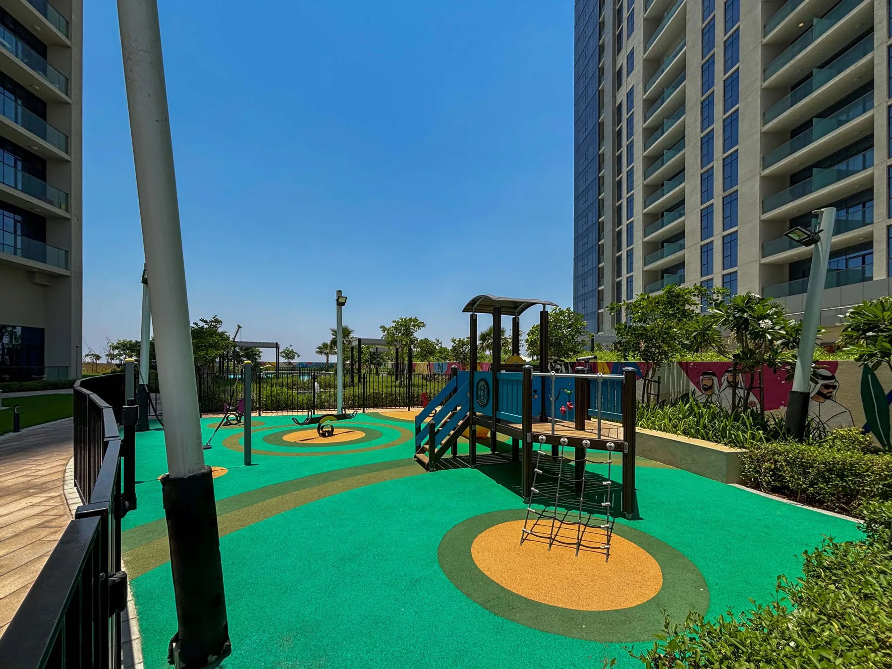 An outdoor playground with colorful climbing equipment between high-rise buildings.