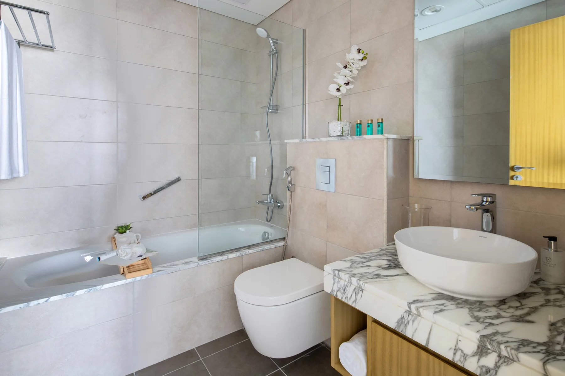 A tiled bathroom with a bathtub, shower, and vanity.